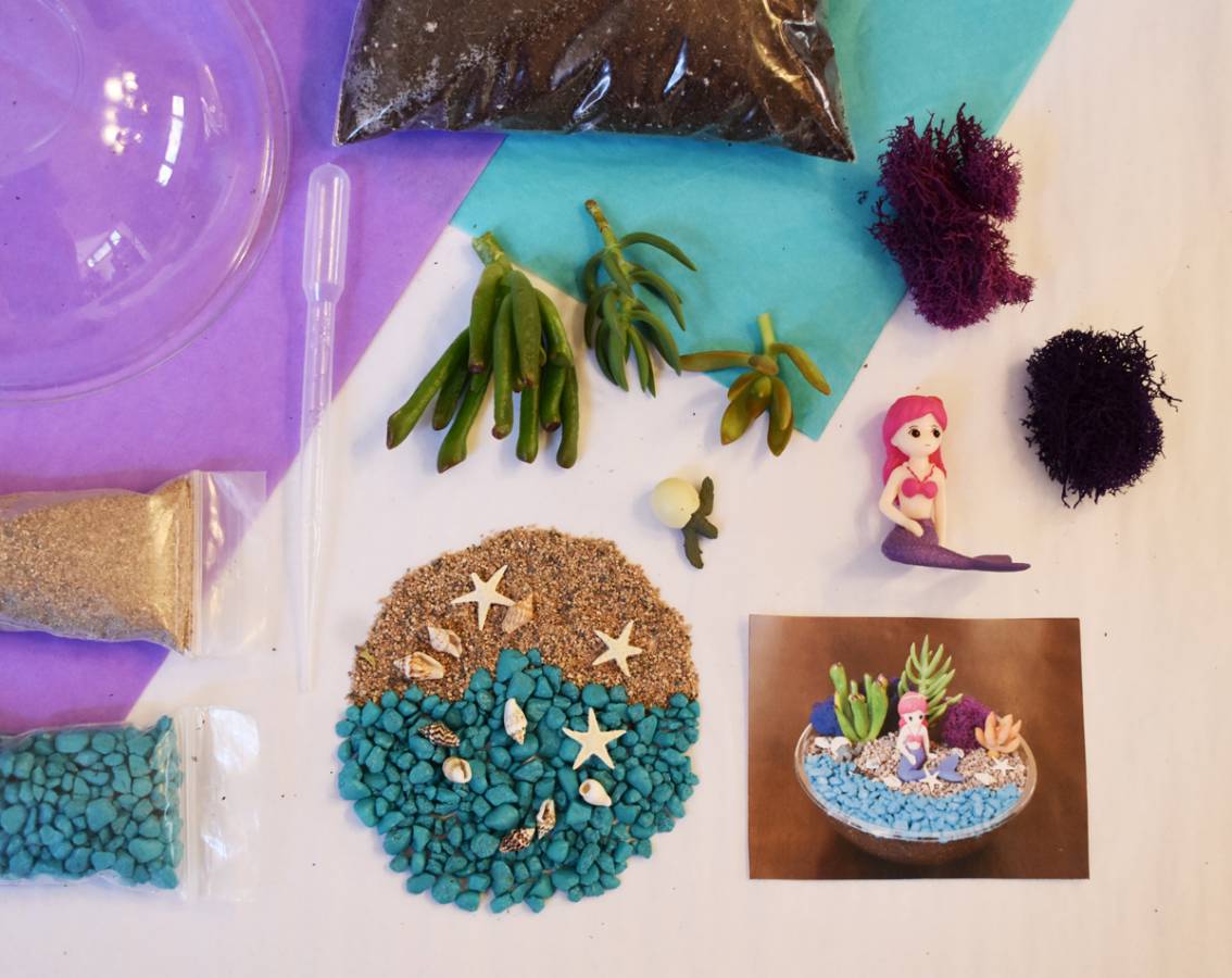 Mermaid-themed craft kit with sea-themed decorations and a small mermaid figurine on a white surface.